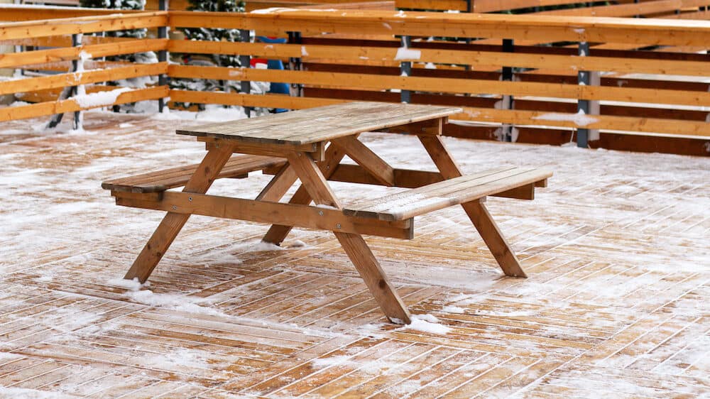 wooden table on patio in winter on snowy ground