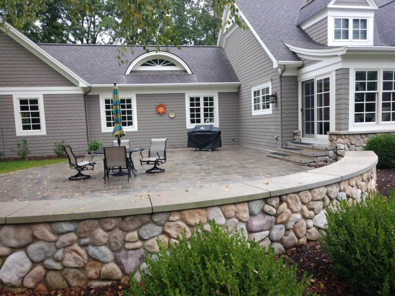 Front Yard and Patio renovation in Ada, MI done by Torchwood Landscaping. Photo shows back patio with decorative stone retaining wall.