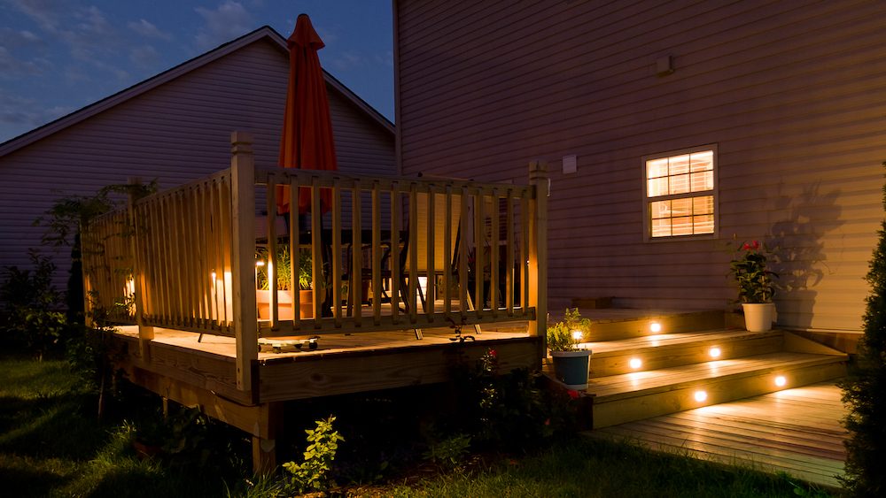 Wooden deck and patio of family home at night.