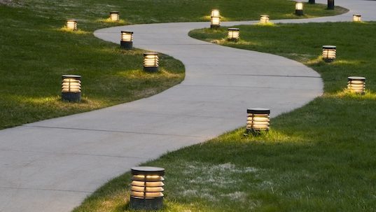 A curving sidewalk lit by small foot lights.