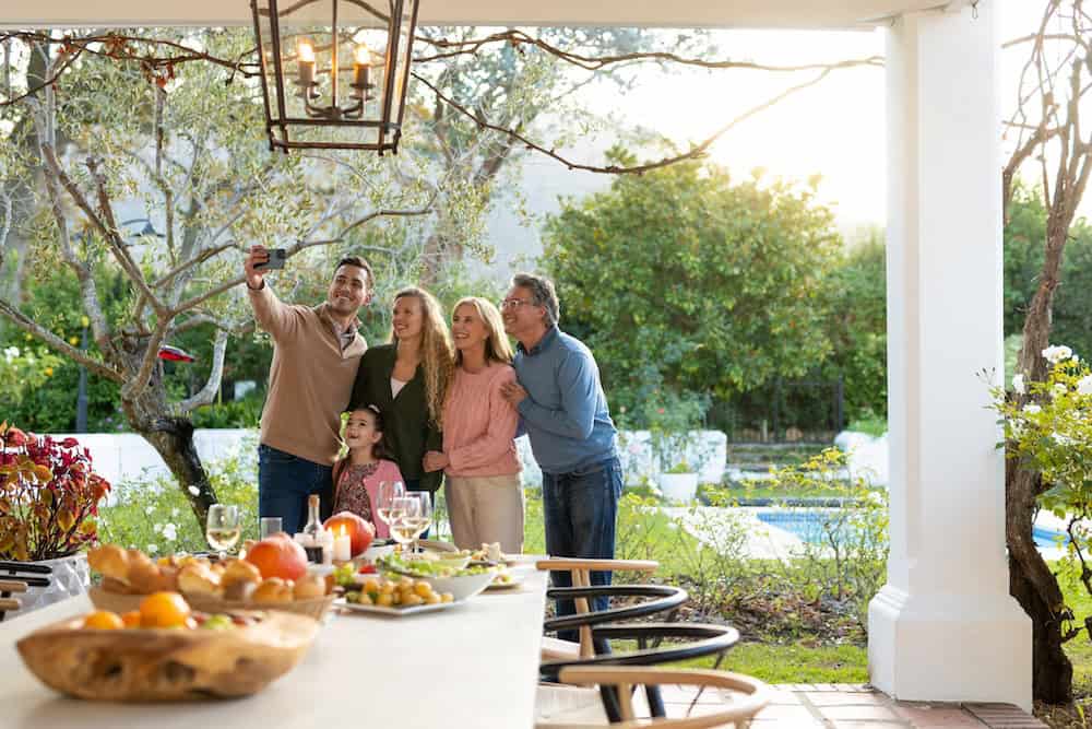 Image of happy multi generation caucasian family taking selfie after dinner on patio