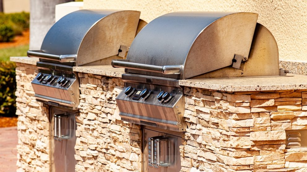 An outdoor kitchen with two grills mounted in a stone counter.