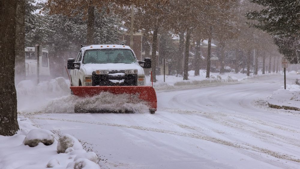 Winter service truck with snowplow removing snow clearing road maintenance in after heavy snowfall